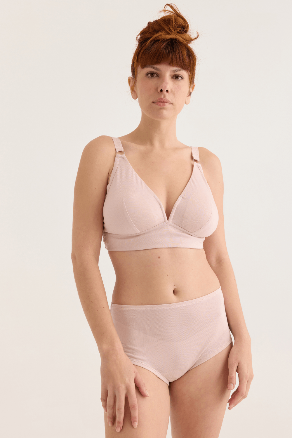 Woman wearing a pink bra and panties set on a plain background