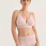 Woman wearing a light pink bikini set against a plain background