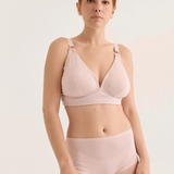 Woman wearing a light pink bikini set against a plain background
