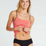 woman wearing a an organic cotton singlet in poppy colour, with black tencel boy leg briefs