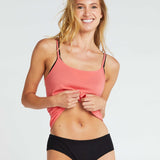 woman wearing a an organic cotton singlet in poppy colour, with black tencel boy leg briefs
